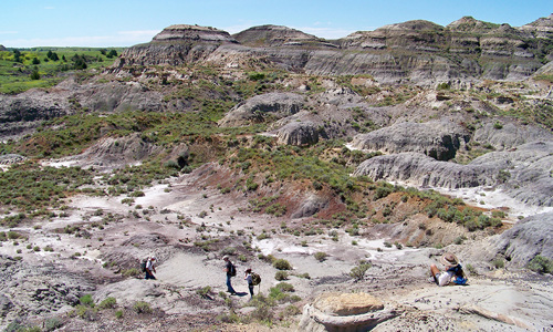 A wide image shot of the Hell Creek area with a couple of people walking in the foreground.